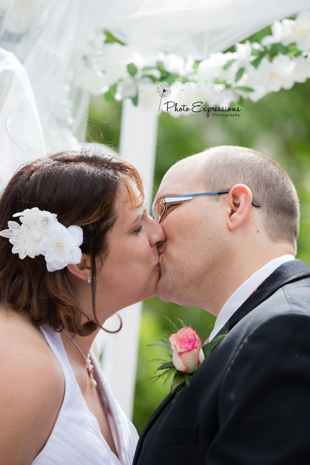 A romantic kiss between newlyweds during an outdoor wedding ceremony.