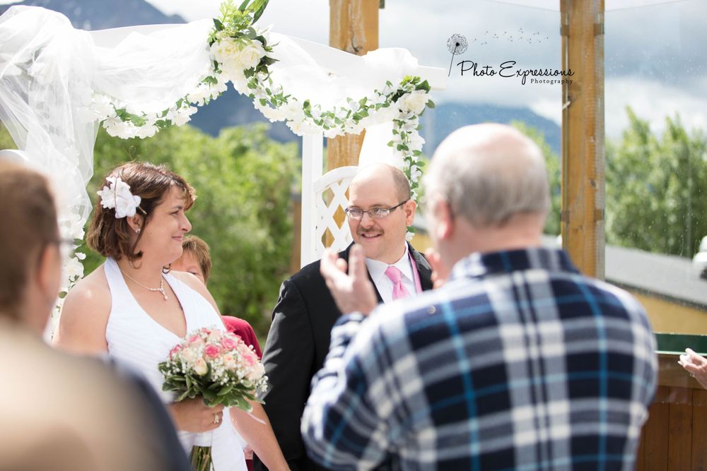 Wedding guests gather under a white canopy during an outdoor celebration.