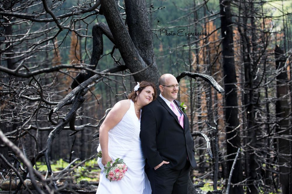 Wedding couple shares intimate moments against a backdrop of dark forest trees.