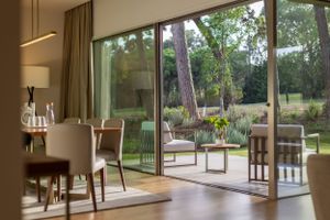 Modern living room with sliding glass doors opening to a garden terrace with outdoor furniture.