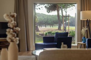 Elegant living space with navy blue chairs and large window overlooking a serene garden view.