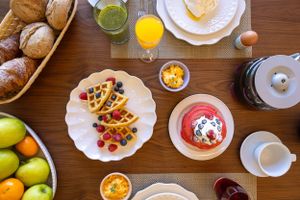Breakfast table spread with fresh fruits, pastries, and colorful plates.