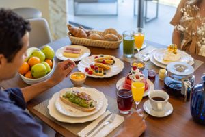A breakfast table spread with orange juice, coffee, sandwiches and fresh fruit.