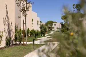 Modern white residential buildings with landscaped gardens and walking paths.
