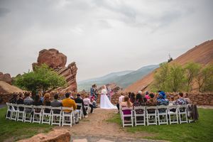 Scenic mountain wedding ceremony at Red Rocks with dramatic landscape and white chairs setup.