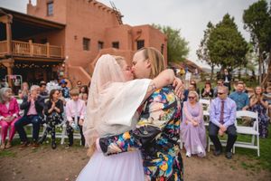 A joyful celebration at an outdoor wedding with guests seated on white chairs.
