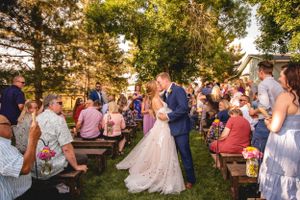 Sunset outdoor wedding reception with guests seated on wooden benches.