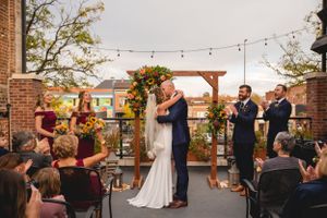 Outdoor rooftop wedding ceremony with string lights and brick walls creating an intimate atmosphere.