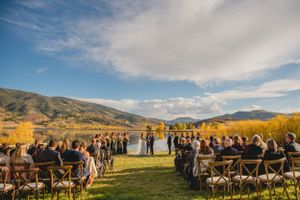 Outdoor wedding ceremony setup with mountain backdrop and fall foliage on a sunny day with dramatic clouds.