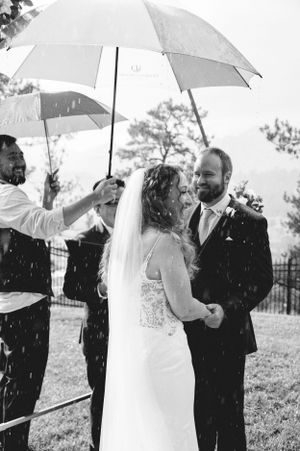 Black and white photo of a wedding ceremony in the rain with people holding umbrellas.