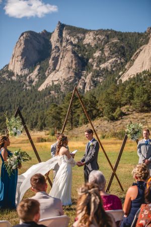 An outdoor wedding ceremony takes place in front of dramatic granite cliffs at Rocky Mountain National Park on a sunny day.