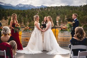 Mountain wedding ceremony with wine barrels and snowy peaks in background.