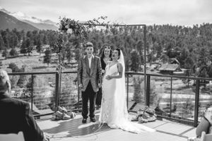 Mountain wedding ceremony on deck with mountain views and rustic wooden arch in black and white.