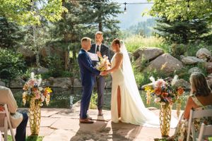 Outdoor wedding ceremony on stone patio with mountain views and floral decorations.