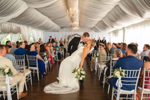 Wedding ceremony kiss in elegant white tent with silver chiavari chairs.