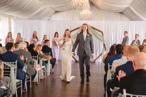 Dancing guests celebrate during a reception in an elegant white tent with crystal chandeliers.