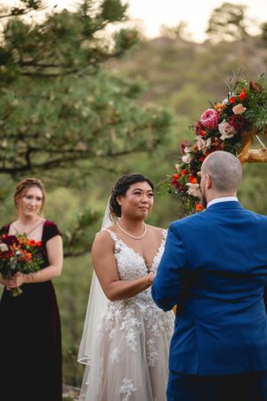 Outdoor wedding ceremony with burgundy and pink floral arch arrangements.