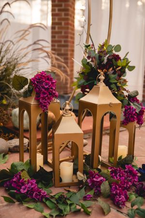 Gold lanterns and vibrant purple floral arrangements create an elegant wedding decoration display.