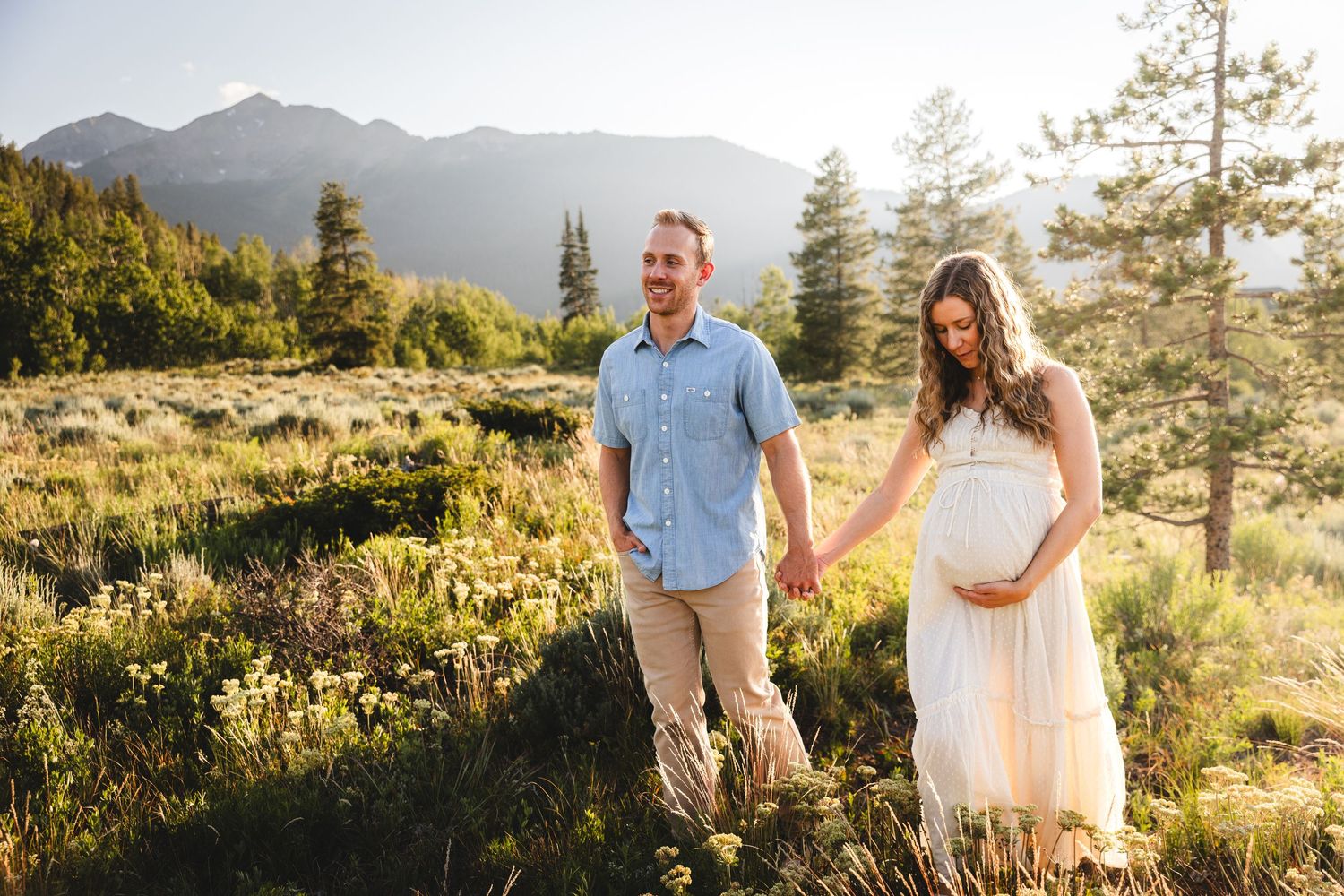 Couple holding hands in mountain meadow during golden hour photoshoot, in Frisco, Colorado - Maternity Couples Session