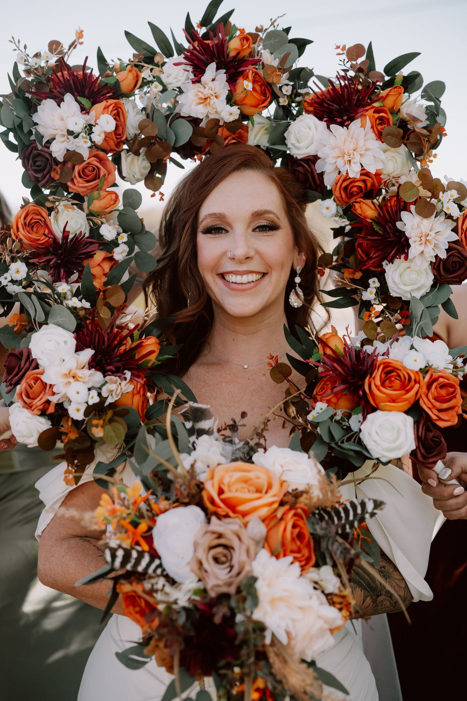 Beautiful autumn wedding bouquet featuring orange roses, burgundy dahlias, and white flowers with greenery.