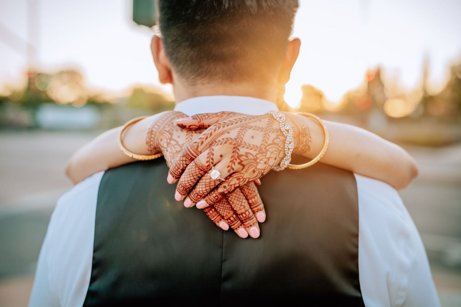 Close up of hands resting together at sunset creating a romantic silhouette against warm glowing light.