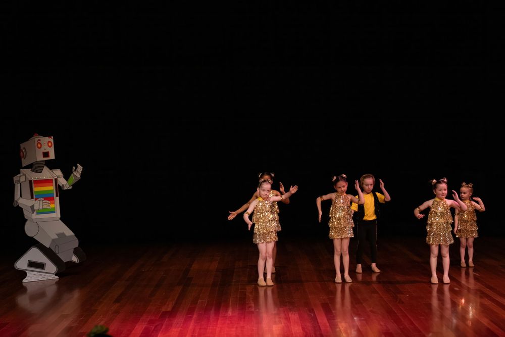 Dance performance featuring performers in tribal-inspired costumes on wooden stage.