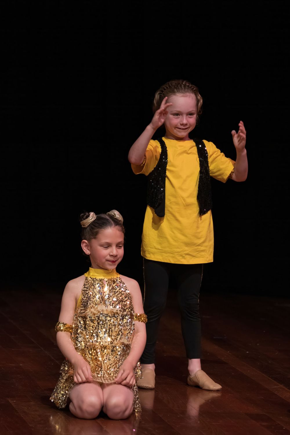 Two performers in contrasting outfits pose dramatically during a dance routine.