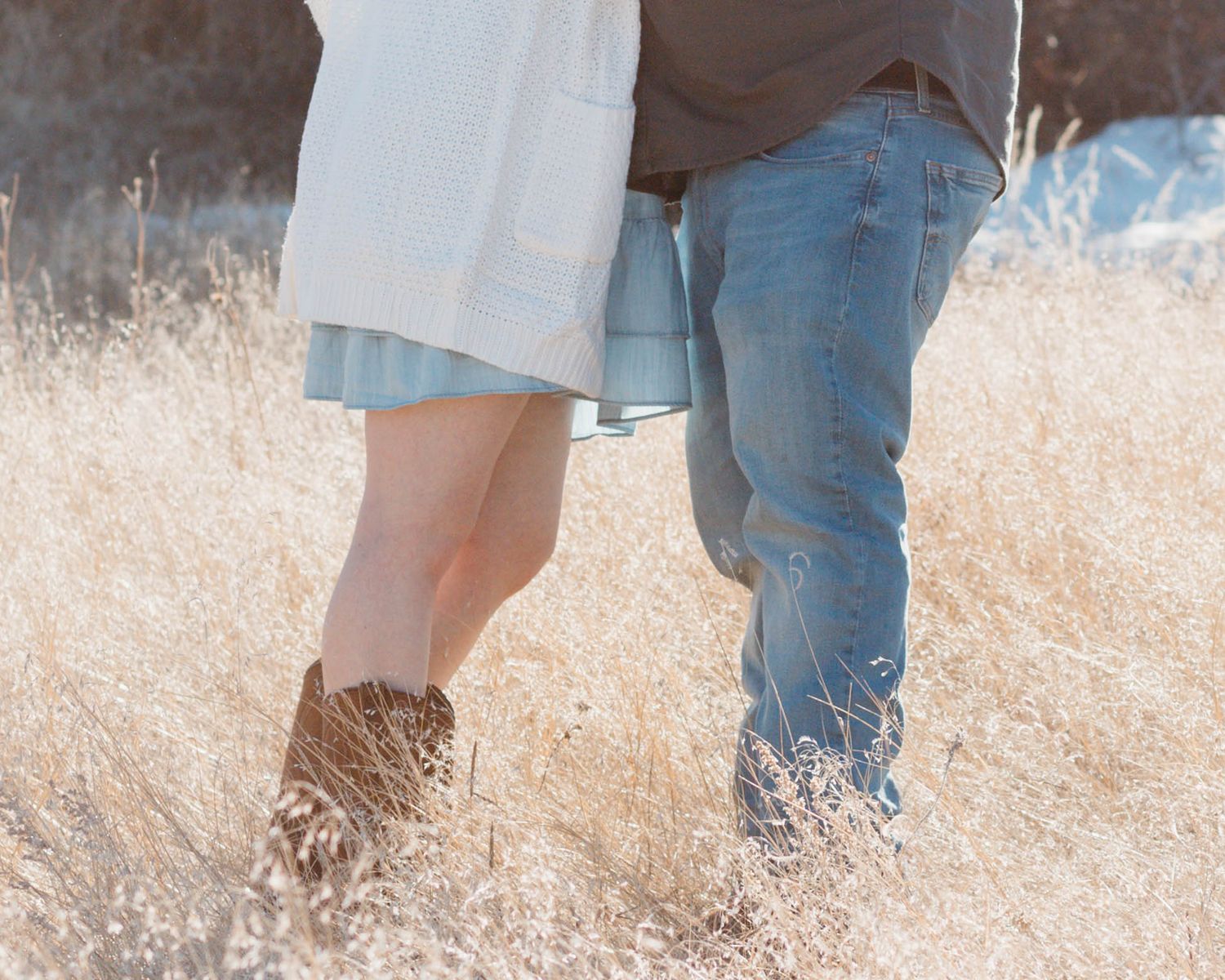 A close-up shot of boots and jeans standing in tall golden grass.