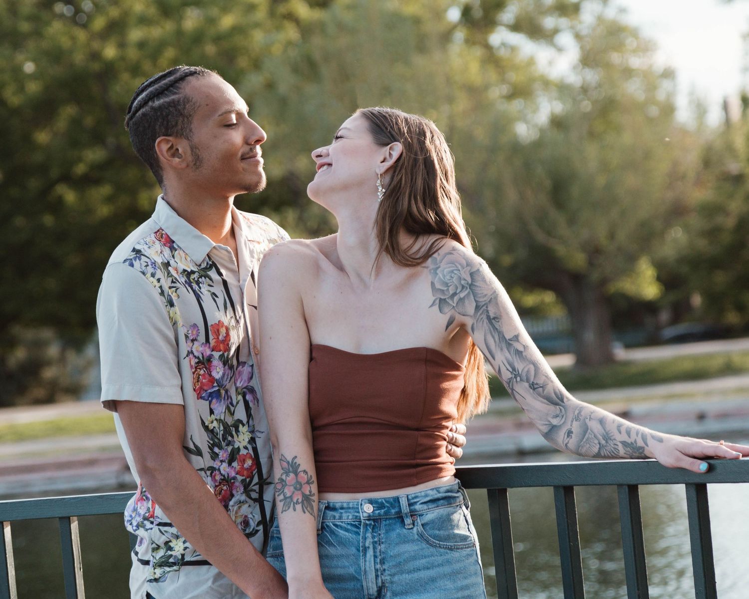 Couple laughing together on a balcony, wearing casual summer outfits.