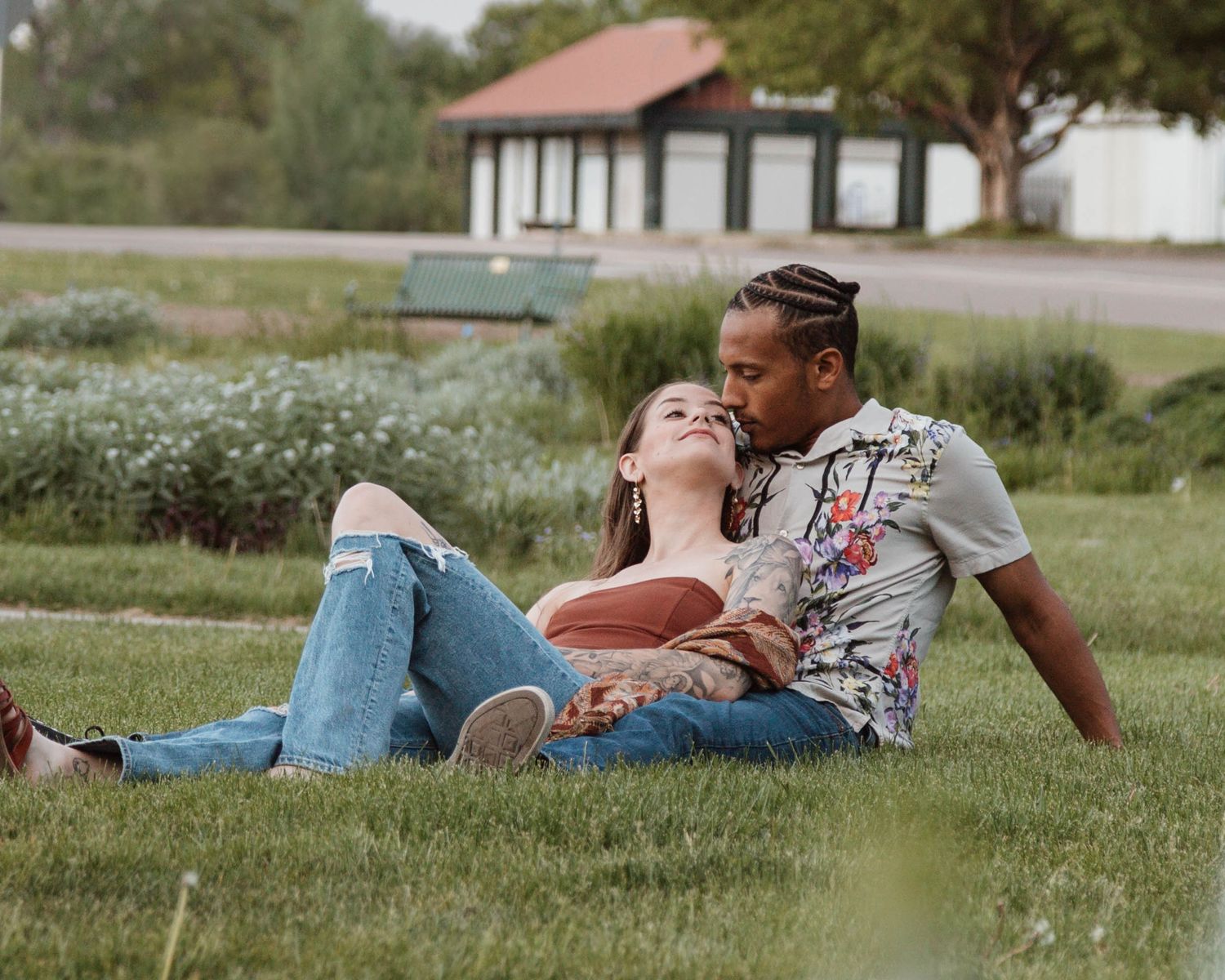 Couple relaxing together on grass near a lake on a sunny day.