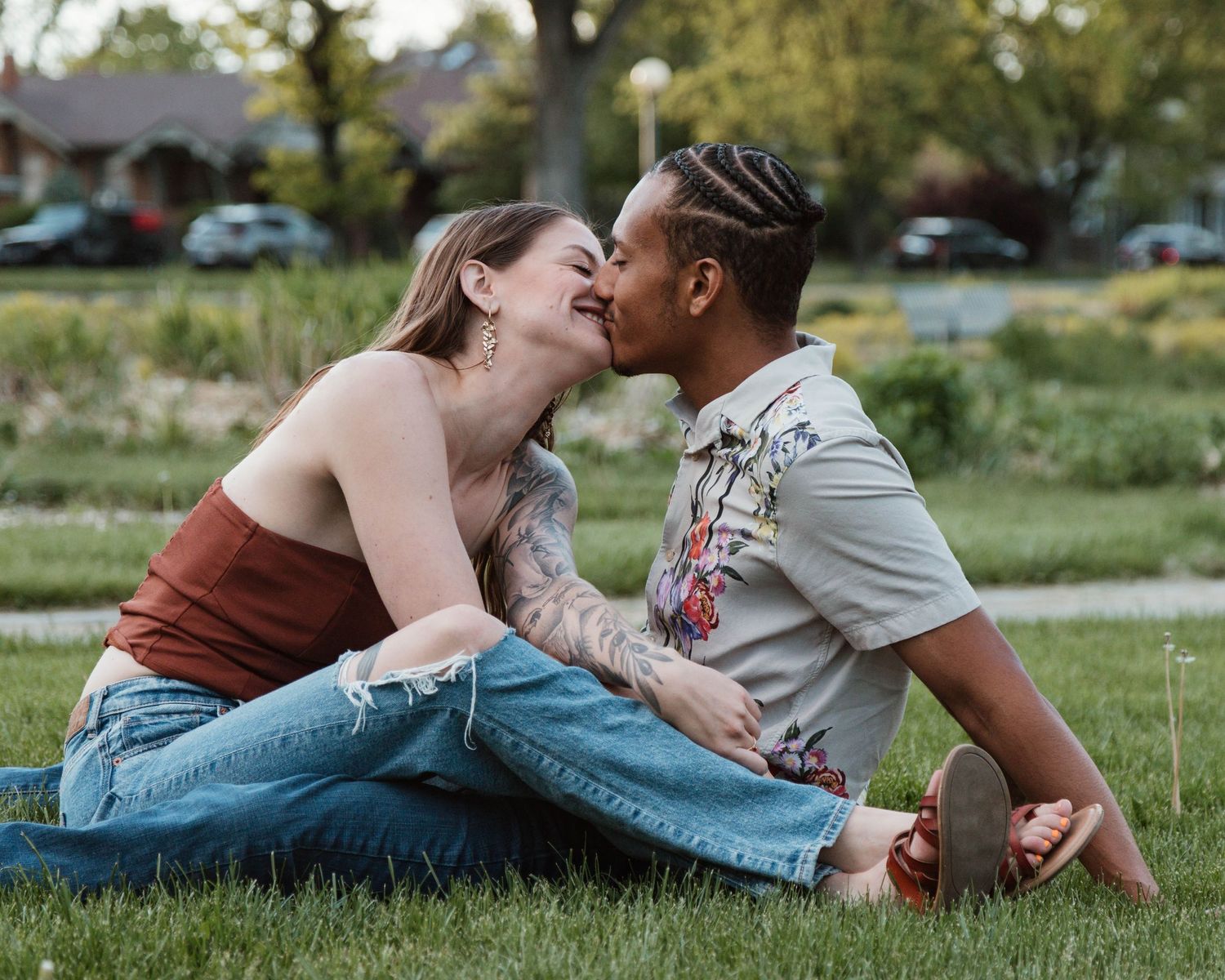 Intimate couple sharing a tender moment while sitting on grass outdoors.