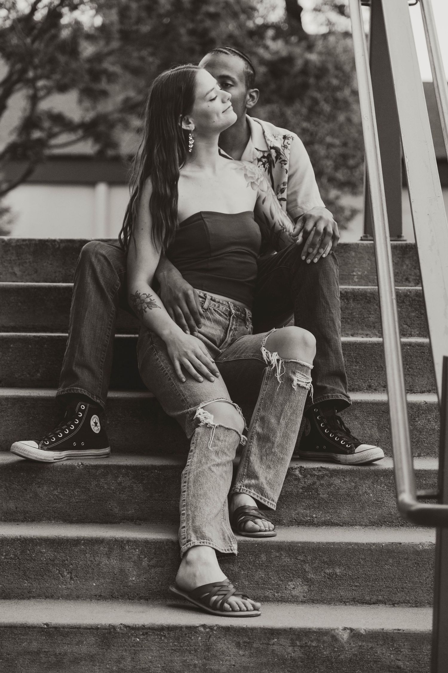 Black and white portrait of couple sitting on concrete steps.