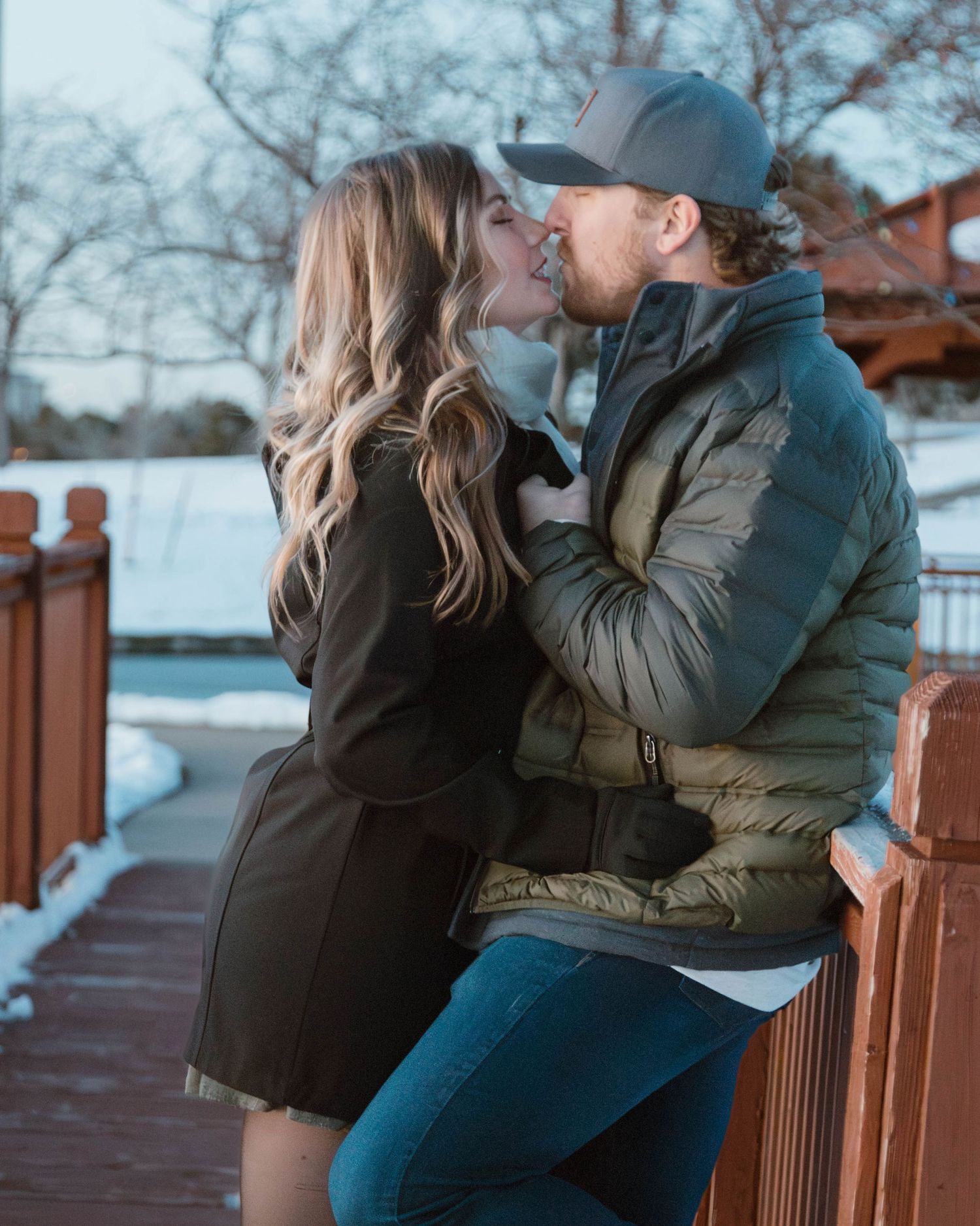 A couple sharing an intimate moment on a wooden bridge during winter.