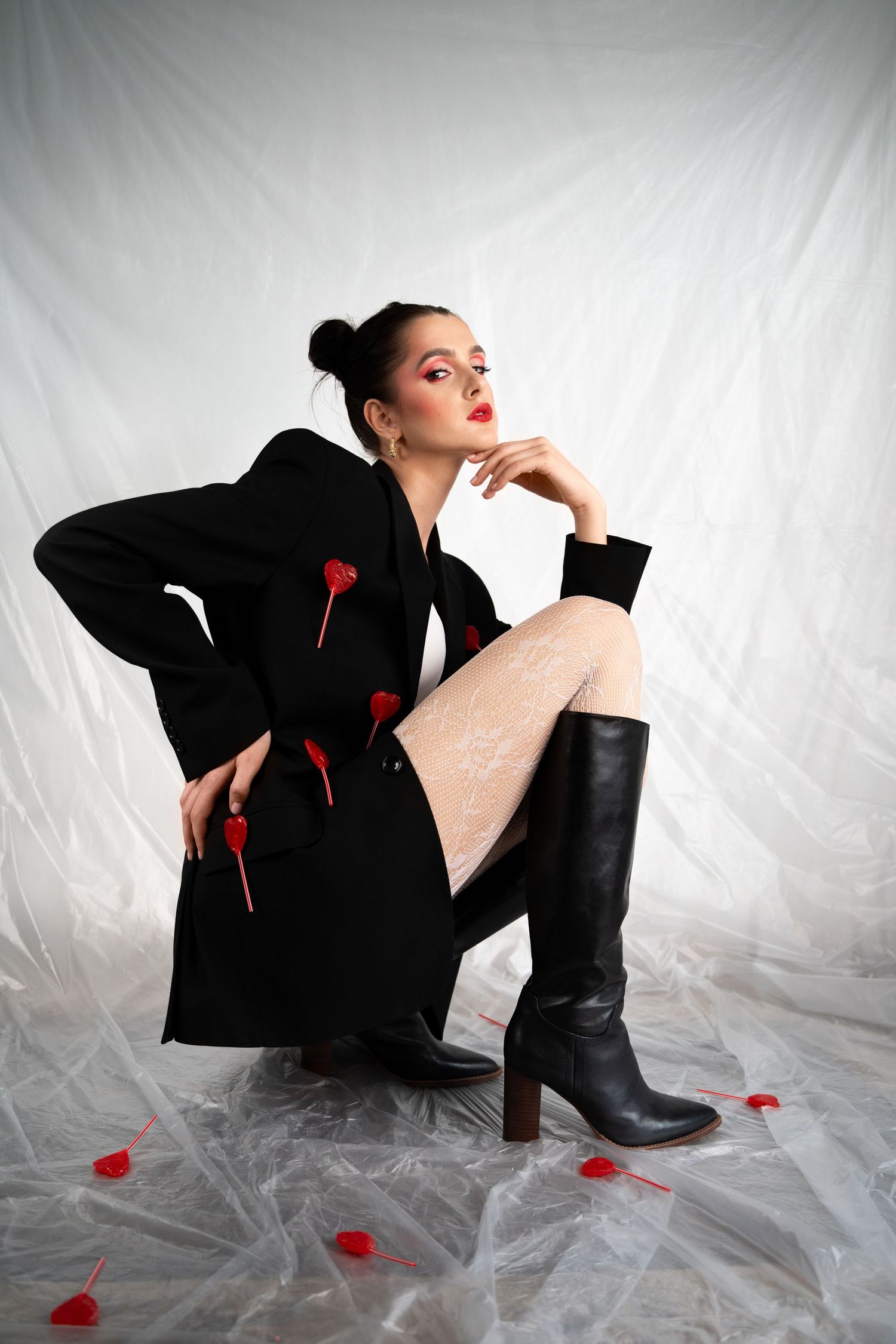 Fashion photo of model in black blazer with red hearts and knee-high boots.
