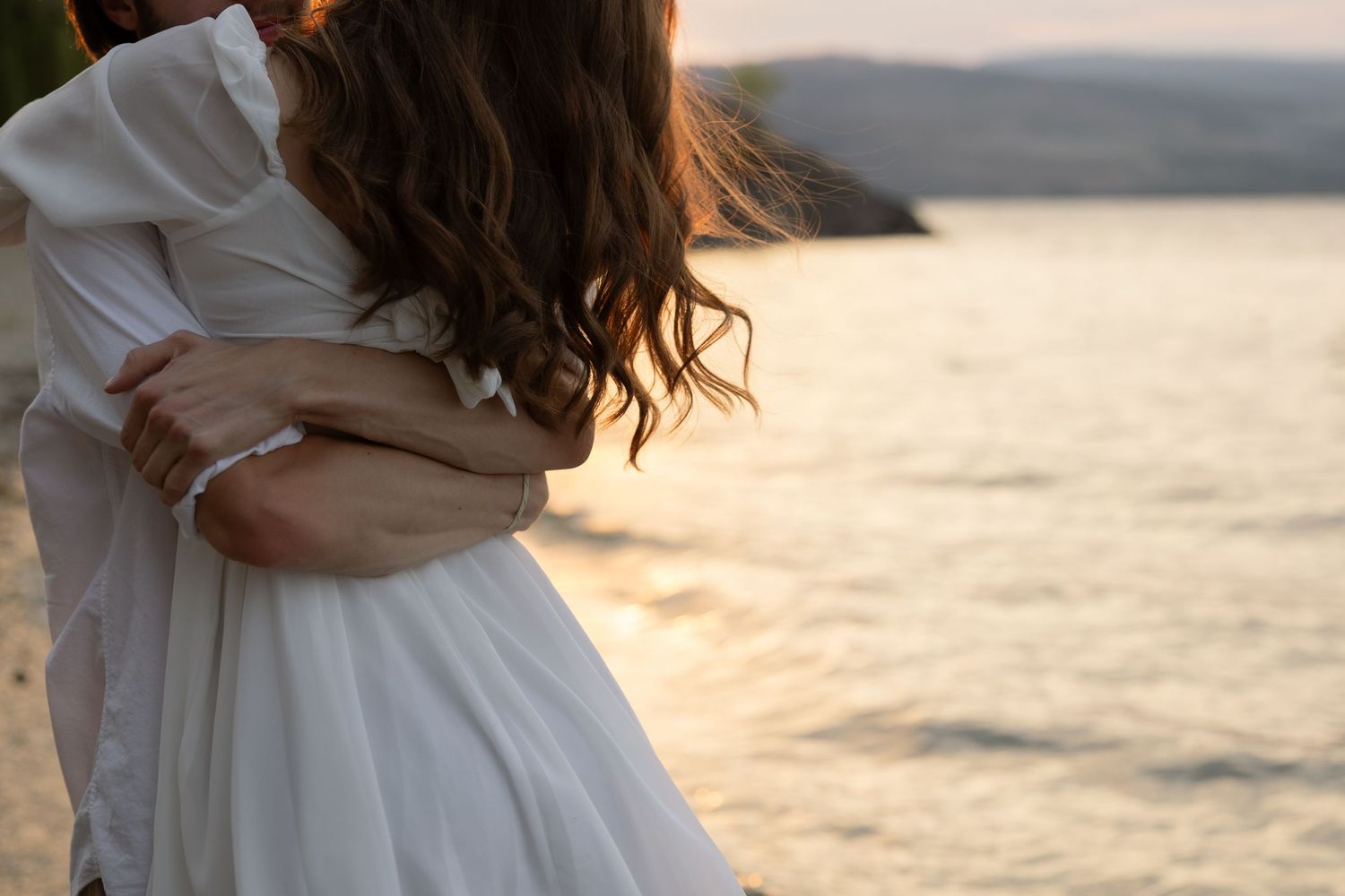 Newlyweds embracing at dusk with Kelowna Okanagan lake in the background