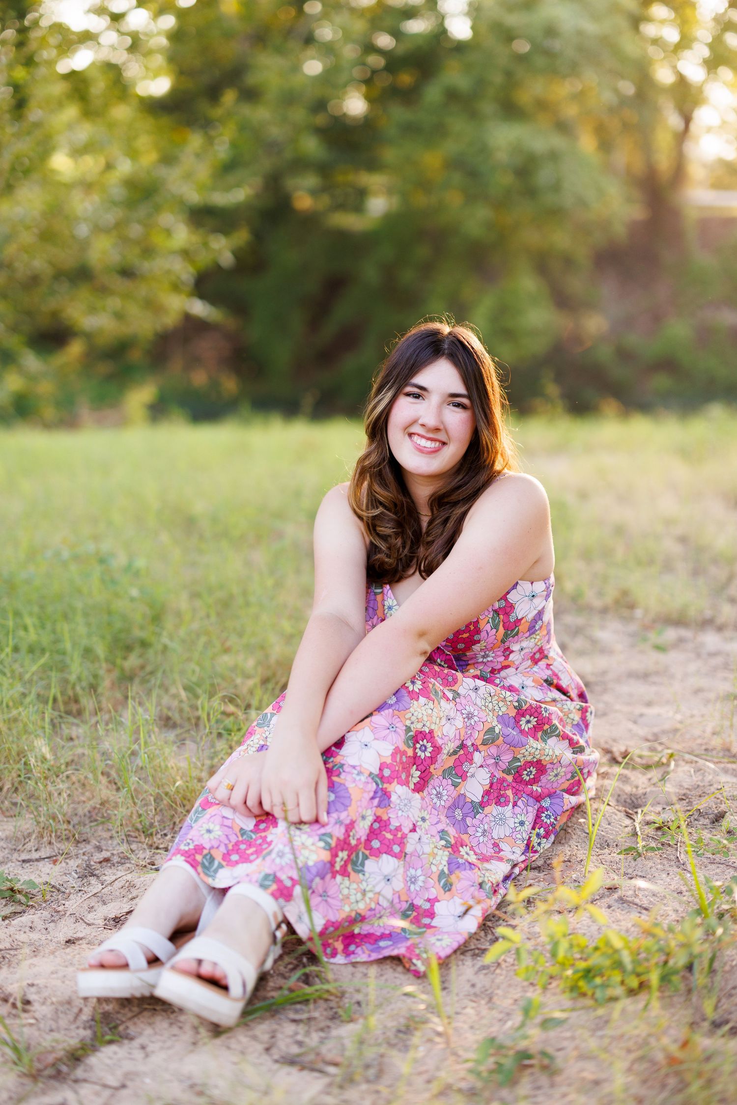 Summer photoshoot in a field with white sandals and a flowing floral dress.