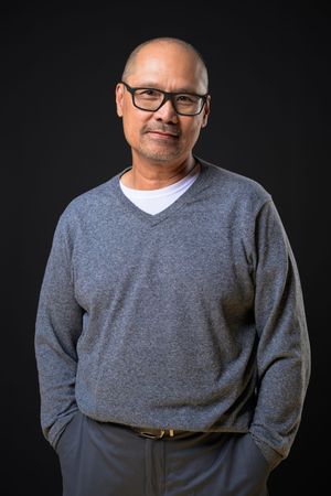 A person in glasses and a gray sweater poses against a black background in a series of cropped portraits.