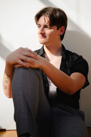 Artistic black and white portrait series showing person in dark clothing against white wall with dramatic shadows.