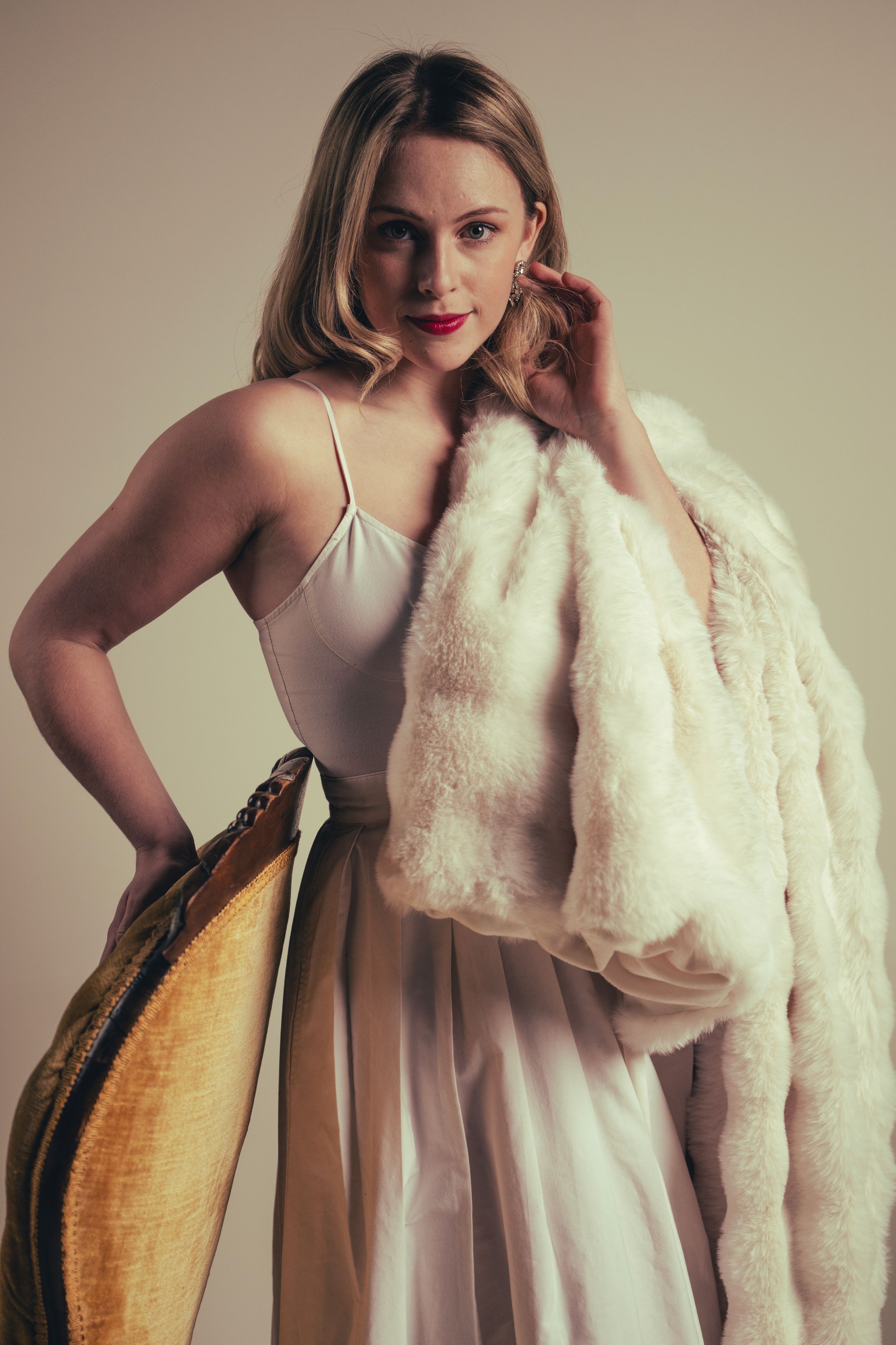 A fashion portrait series showing a model in a white dress and fur stole posing against a neutral background.