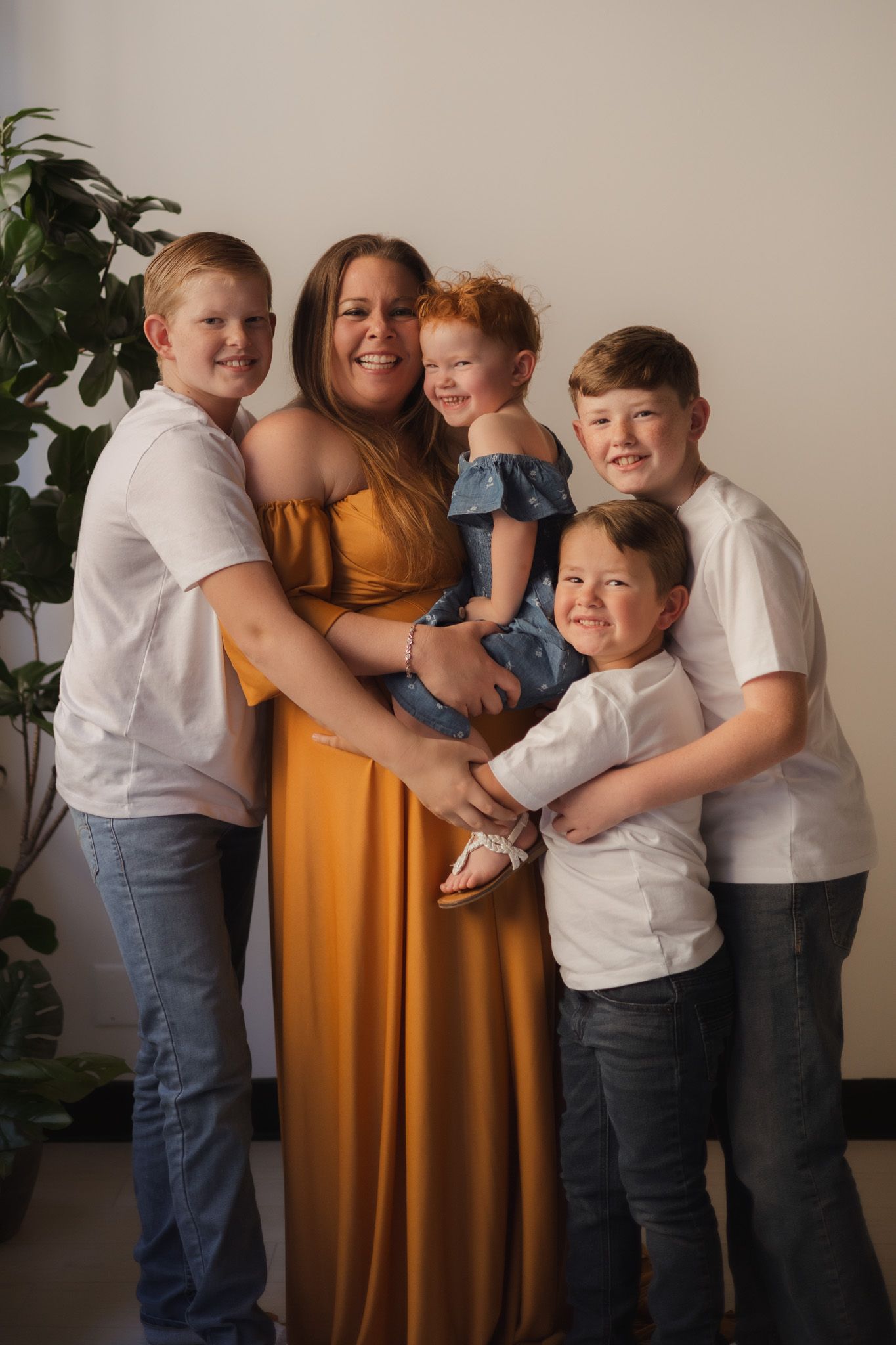 Family portrait with children and parent in yellow dress against neutral background. Spokane family photographer.
