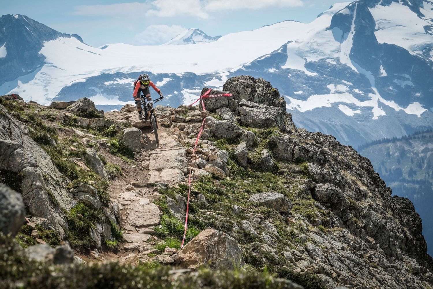 Mountain biker traverses rocky alpine trail with snow-capped peaks in background.
Whistler Mountain Bike Park
Crankworx