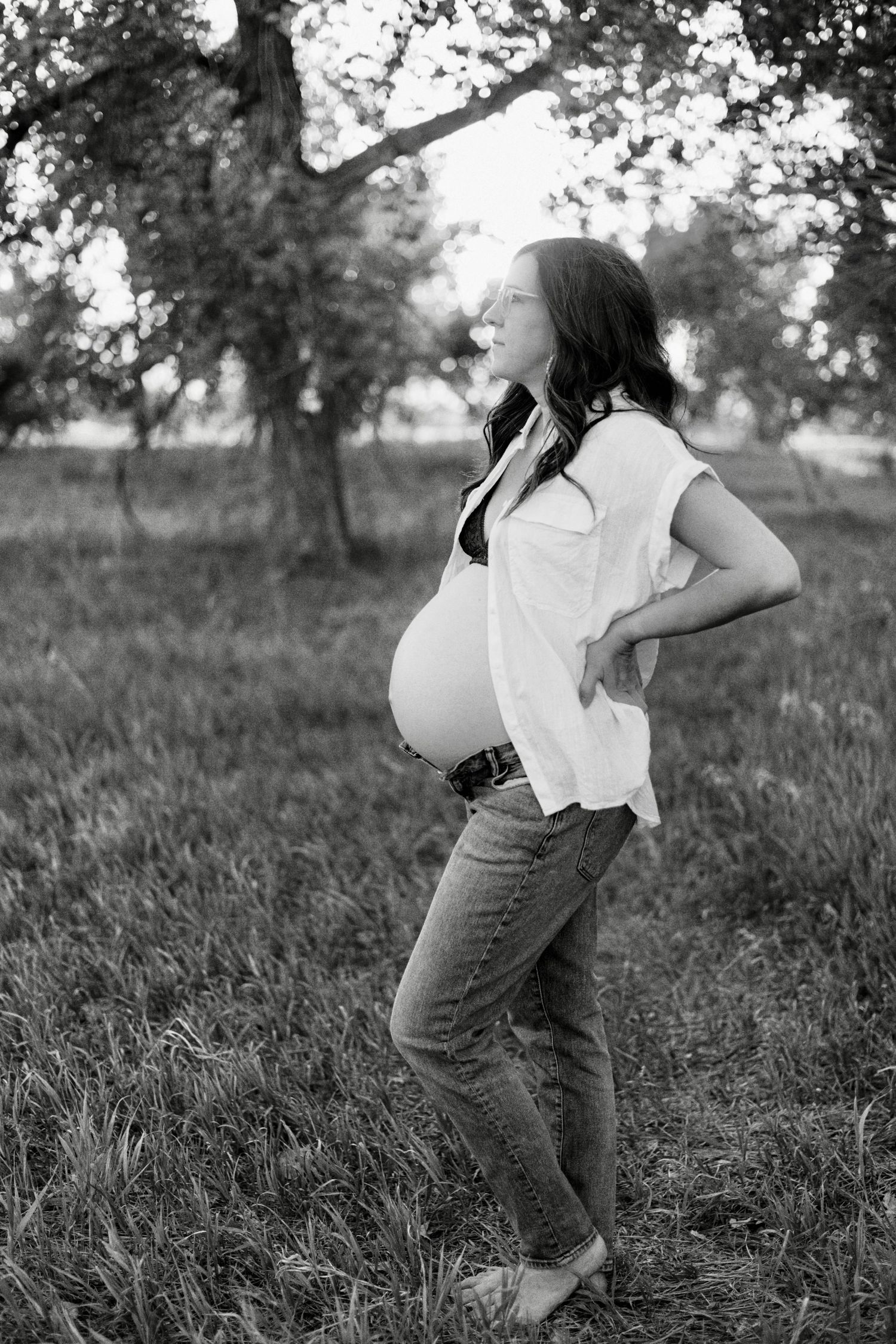 Black and white maternity photo showing side profile of expectant mother standing in a field.