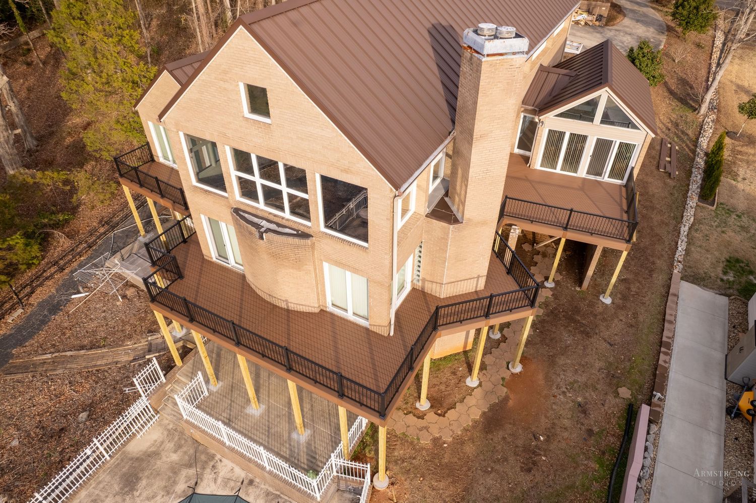 Aerial drone view of multiple residential homes with brown roofs and landscaped yards in a suburban neighborhood.