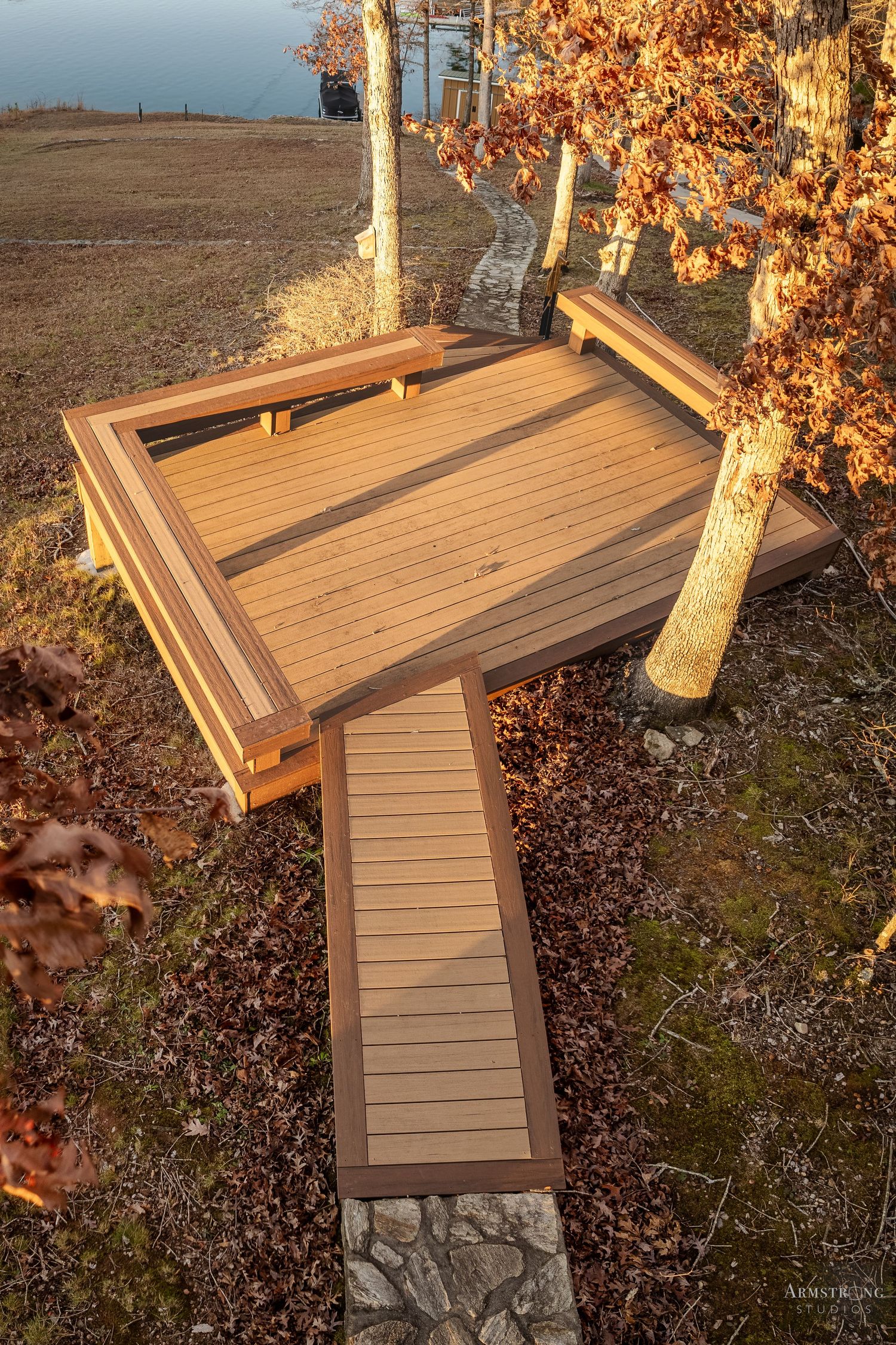 A series of composite deck boards being installed on an outdoor structure with stone base during autumn season.