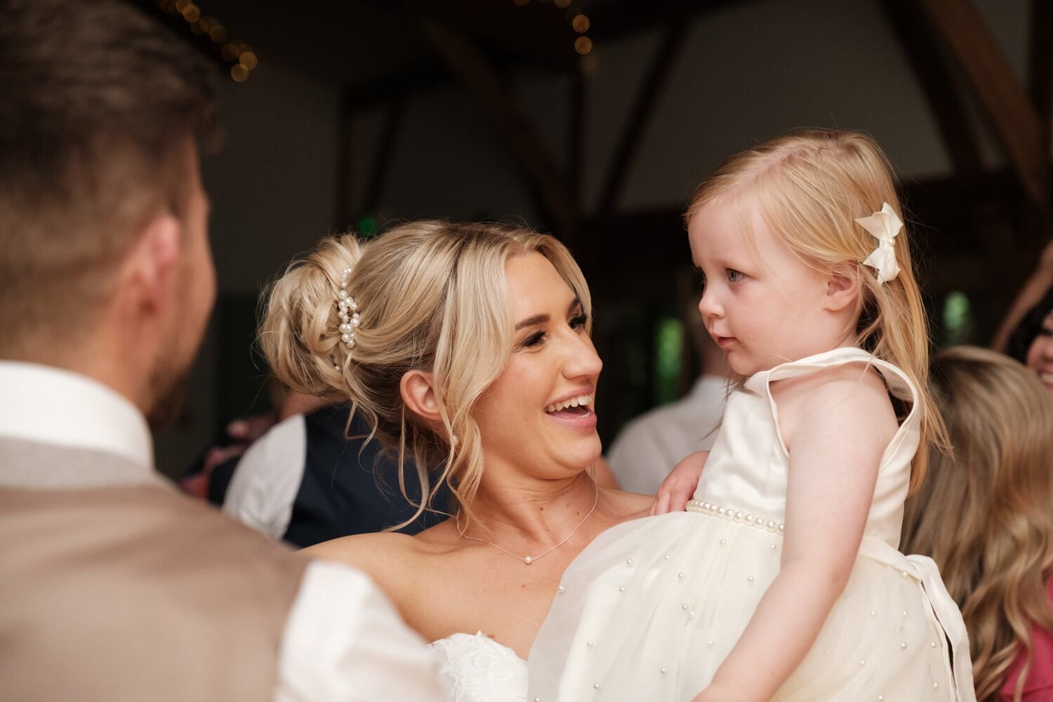 Bride holding a young girl while smiling.