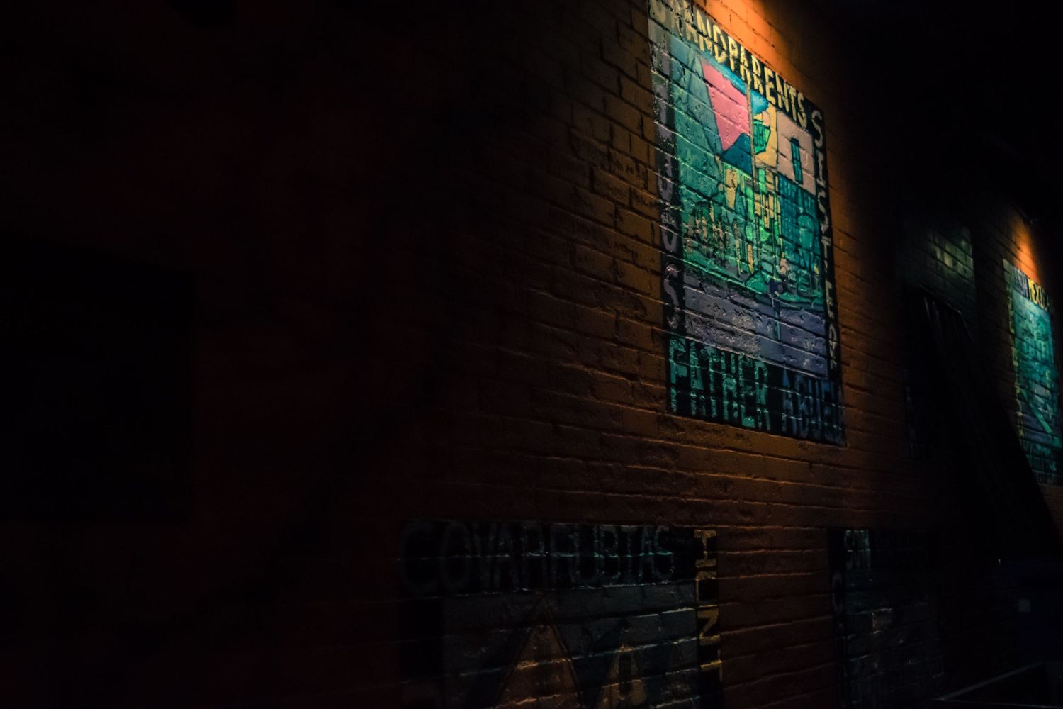 Vintage poster illuminated on brick wall at night with green tint.