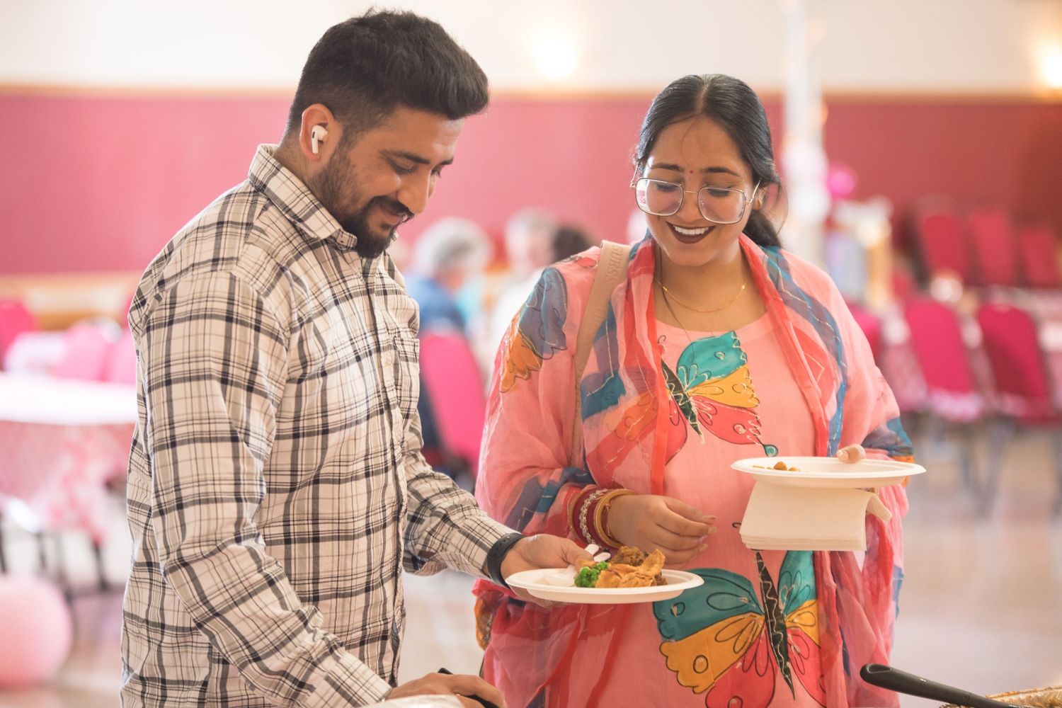 Couple selecting food together at casual dining event with pink walls.