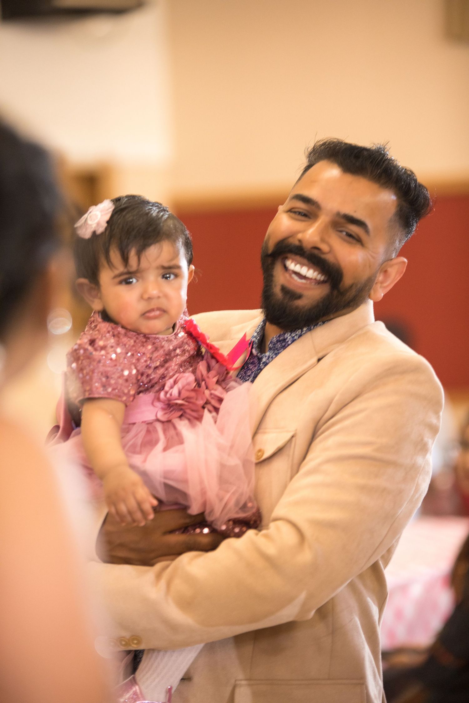 Happy moment at celebration with person holding child in pink dress.
