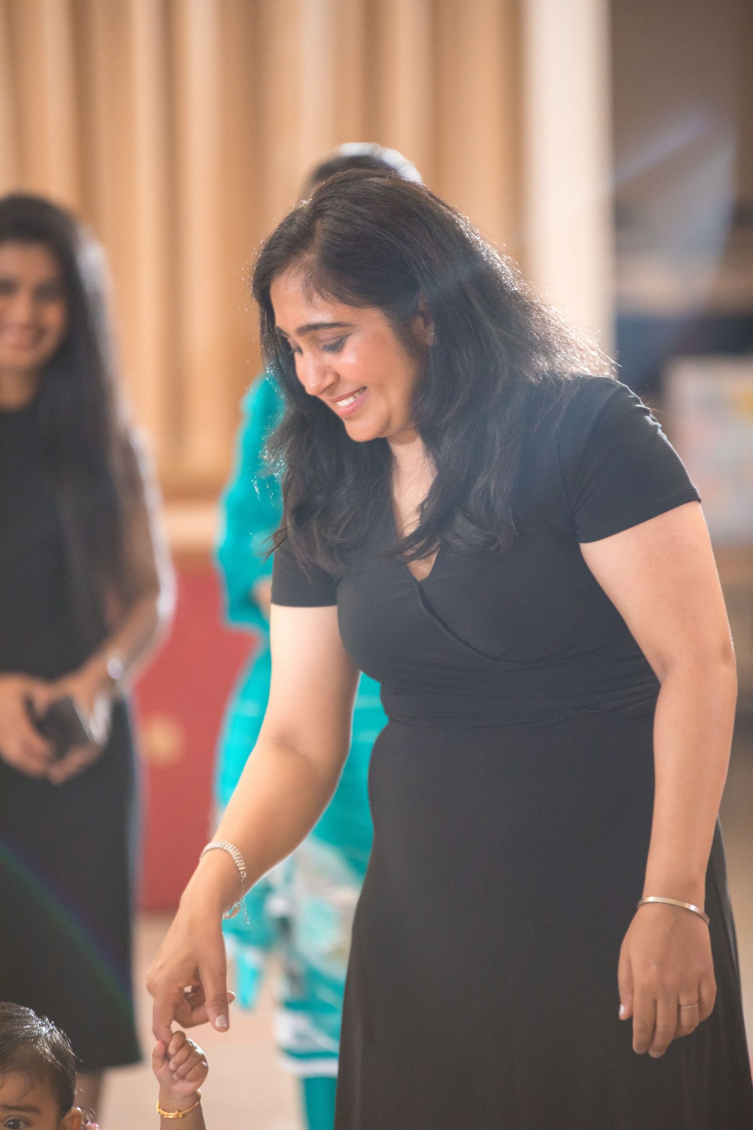 Person in a black dress interacting at what appears to be a social gathering.