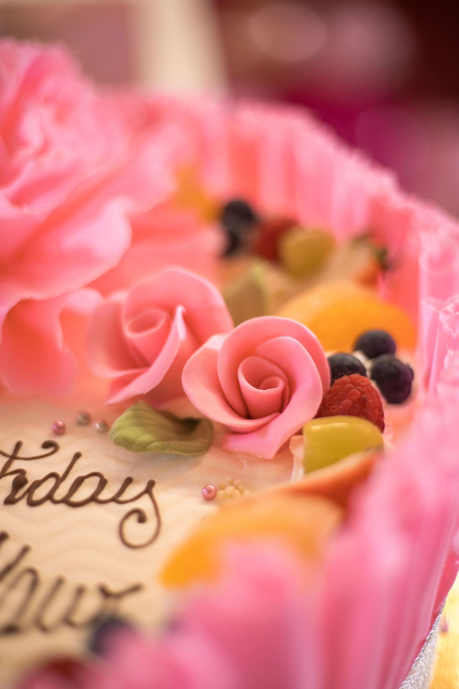 Close-up of pink fondant roses and decorative elements on a birthday cake.